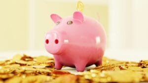Tirelire rose sur un tas de pièces d'or – Économiser pour un PVT en Australie et financer son voyage en Working Holiday Visa.